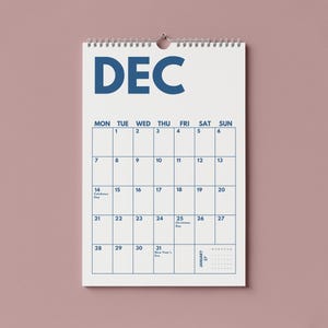 Pu&ograve; includere: Un calendario da parete bianco per il mese di dicembre con testo e linee della griglia in blu scuro. Il calendario presenta una rilegatura a spirale nella parte superiore, i giorni della settimana da luned&igrave; a domenica e date da 1 a 31 in blu.