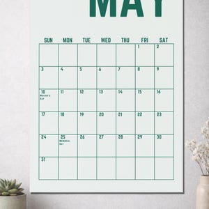 May include: A white wall calendar for the month of May, with a green font. The calendar grid is outlined in green. The 10th is labeled "Mother's Day" and the 25th is labeled "Memorial Day".