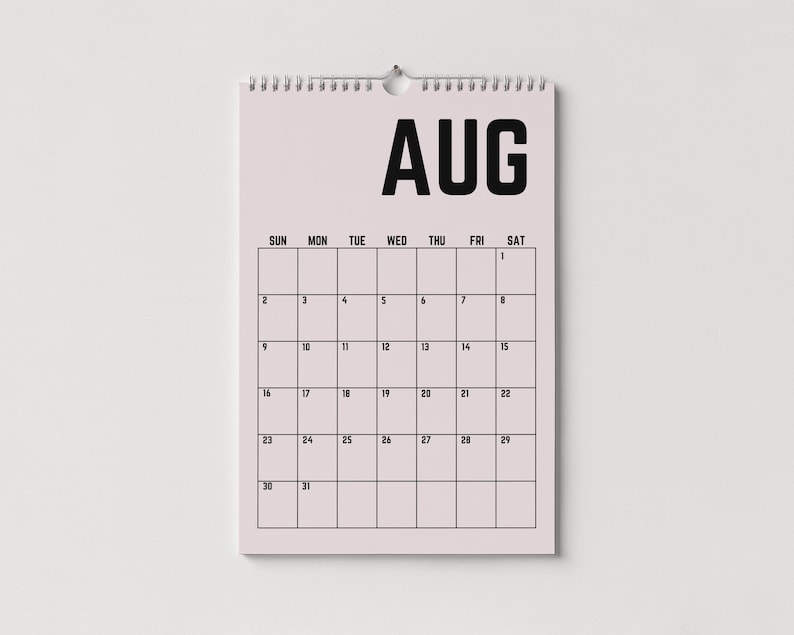 Peut inclure: Calendrier mural rose clair pour le mois d'ao&ucirc;t. Le mot "AUG" est en haut, en noir, au-dessus d'une grille de dates. Le calendrier est reli&eacute; par une spirale en haut et est suspendu &agrave; une boucle m&eacute;tallique.