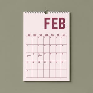 May include: A wall calendar for February 2017, with a pink background and dark pink grid lines. The word "FEB" is printed at the top. The calendar is hanging on a wall with a neutral green color.