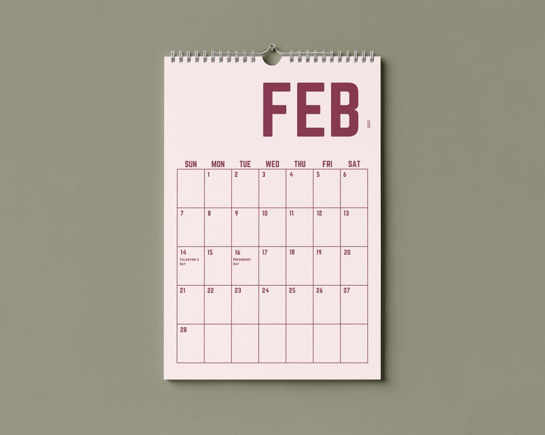 May include: A wall calendar for February 2017, with a pink background and dark pink grid lines. The word "FEB" is printed at the top. The calendar is hanging on a wall with a neutral green color.