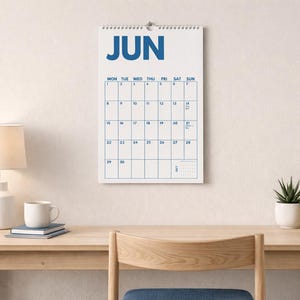 Pu&ograve; includere: Un calendario da parete in carta per il mese di giugno, caratterizzato da uno sfondo bianco con testo blu in grassetto e una disposizione a griglia. Il calendario mostra i giorni della settimana e le date in un formato chiaro, con rilegatura a spirale.