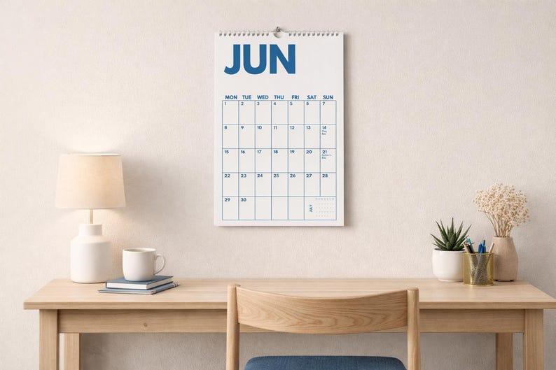 Pu&ograve; includere: Un calendario da parete in carta per il mese di giugno, caratterizzato da uno sfondo bianco con testo blu in grassetto e una disposizione a griglia. Il calendario mostra i giorni della settimana e le date in un formato chiaro, con rilegatura a spirale.
