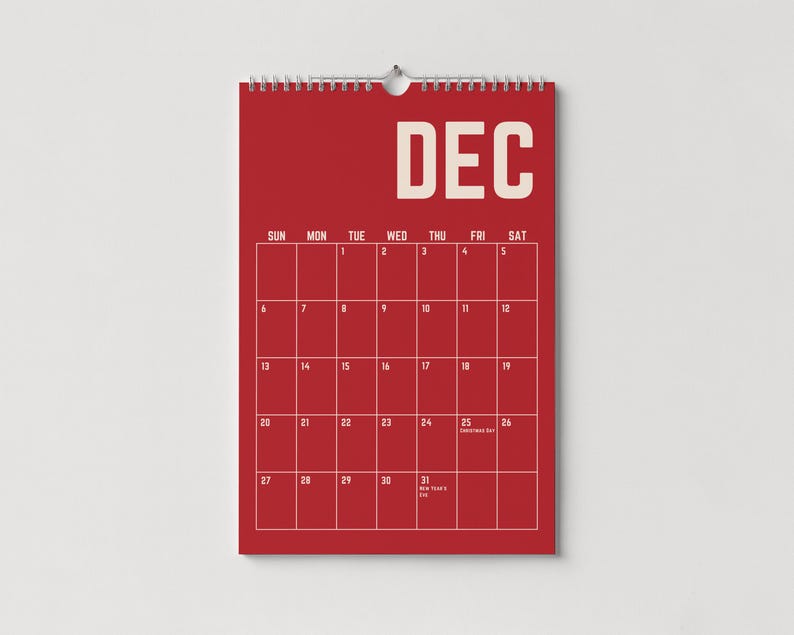 Pode incluir: Um calend&aacute;rio de parede vermelho para dezembro, com uma grade de datas e dias da semana. A palavra "DEC" est&aacute; no topo em letras brancas. O calend&aacute;rio est&aacute; pendurado em uma parede branca.