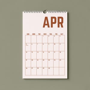 May include: A wall calendar for April, featuring a spiral binding and a simple design. The word "APR" is printed in a bold, brown font at the top. The calendar grid is outlined in brown, with dates and days of the week clearly marked.