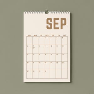 May include: A beige wall calendar for September, hanging against a muted green background. The word "SEP" is printed in a bold, brown font at the top. The calendar grid is visible, with dates and days of the week.