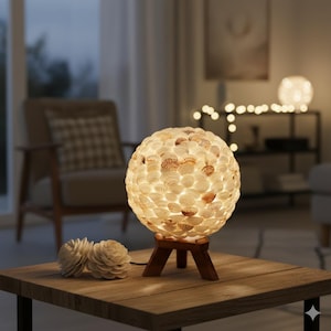 May include: A spherical lamp made of seashells, resting on a wooden tripod base. The lamp emits a warm, inviting glow. Two decorative wooden flowers sit on the table. The lamp is a unique home decor item.