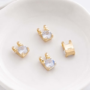 May include: Four gold-toned jewelry charms, each featuring a single round clear cubic zirconia stone set in a prong setting. Three charms display the stone facing upward, while one charm is flipped to show the smooth back stamped with the text S925.