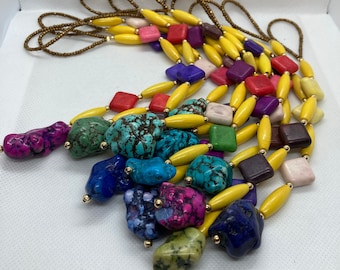 May include: A set of colorful beaded necklaces with yellow, turquoise, purple, red, and green beads. The necklaces are made with natural stones and wooden beads.