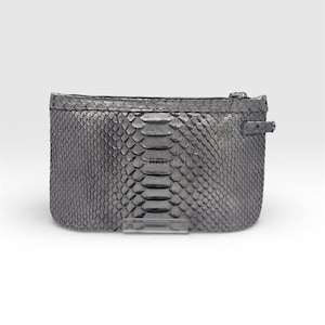Op de afbeelding: Een rechthoekige, zilverkleurige clutch met ritssluiting. De clutch heeft een getextureerd, geschubd patroon, dat op slangenleer lijkt. Een klein lipje en een helder plastic accent zijn zichtbaar aan de voorkant.