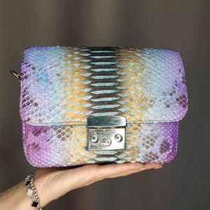 May include: White ceramic mug with a black handle, featuring the text "But First, Coffee" in black. The mug is displayed against a blurred backdrop, implying a comfortable environment.