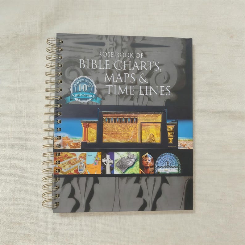 May include: A spiral-bound book titled "Rose Book of Bible Charts, Maps & Time Lines" with a dark gray cover. The cover features architectural illustrations and a 10th Anniversary seal. The book's spiral binding is gold-colored.
