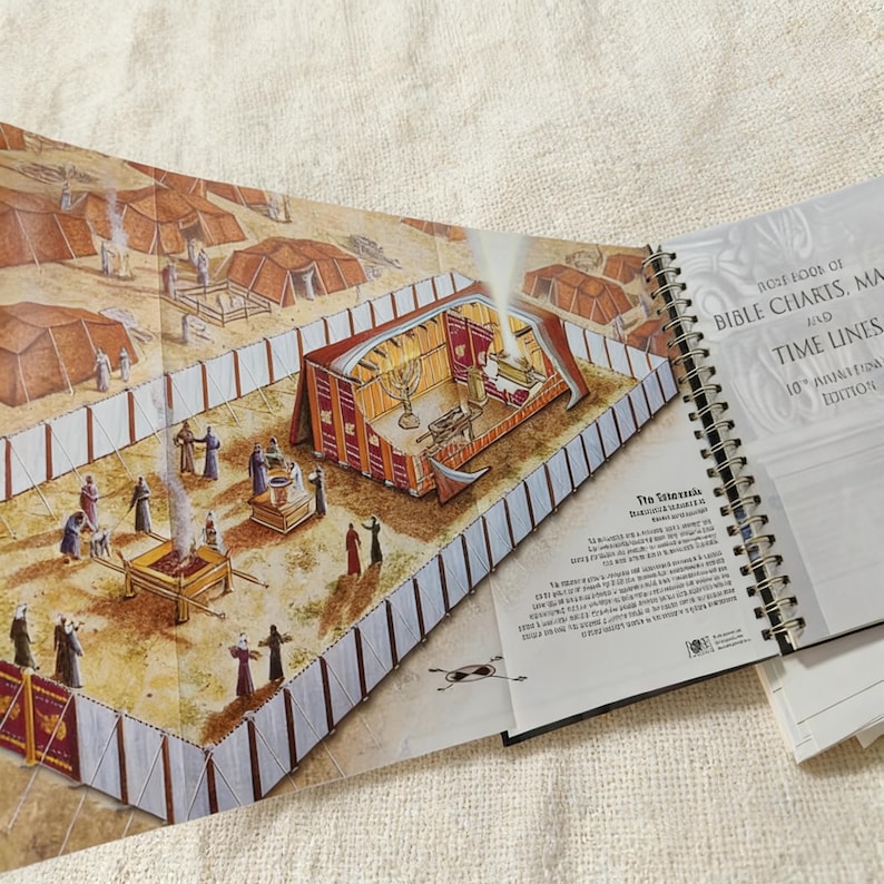 May include: Open book with a detailed illustration of a biblical scene, featuring a tent-like structure with figures and objects. The text "BIBLE CHARTS, MAPS AND TIME LINES" is visible on the right page. The book is spiral-bound.