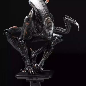May include: A detailed black Xenomorph figure, posed in a crouching position. The creature has a long, segmented tail and sharp claws. The figure is set against a dark background, highlighting its intricate design and menacing appearance.