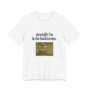 Puede incluir: Camiseta blanca con el texto "mentally I'm in the backrooms." La camiseta presenta una pequeña imagen de un largo pasillo vacío con paredes amarillentas y luces fluorescentes. La camiseta está hecha de un material suave y cómodo.