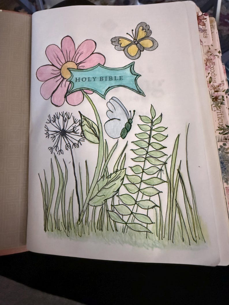 Puede incluir: Una p&aacute;gina de una Santa Biblia con una ilustraci&oacute;n dibujada a mano de una flor rosa con una pancarta verde azulado con la etiqueta HOLY BIBLE, un diente de le&oacute;n, follaje verde y dos mariposas, una amarilla y gris y la otra azul claro, coloreadas.