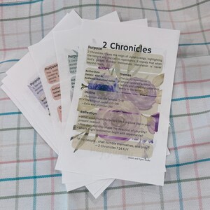 Puede incluir: Una pila de gu&iacute;as de estudio en papel blanco con ilustraciones florales en tonos morados y verdes. La hoja superior se titula 2 Chronicles e incluye secciones para prop&oacute;sito, autor, fecha, audiencia, temas, esquema, reflexi&oacute;n y un vers&iacute;culo.
