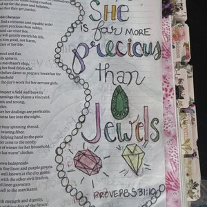 Puede incluir: Una p&aacute;gina de la Biblia con ilustraciones y caligraf&iacute;a hechas a mano. El texto dice, She is far more precious than Jewels, Proverbs 31:10. La p&aacute;gina incluye un collar de perlas dibujado, un diamante azul y gemas verde, rosa y amarilla.