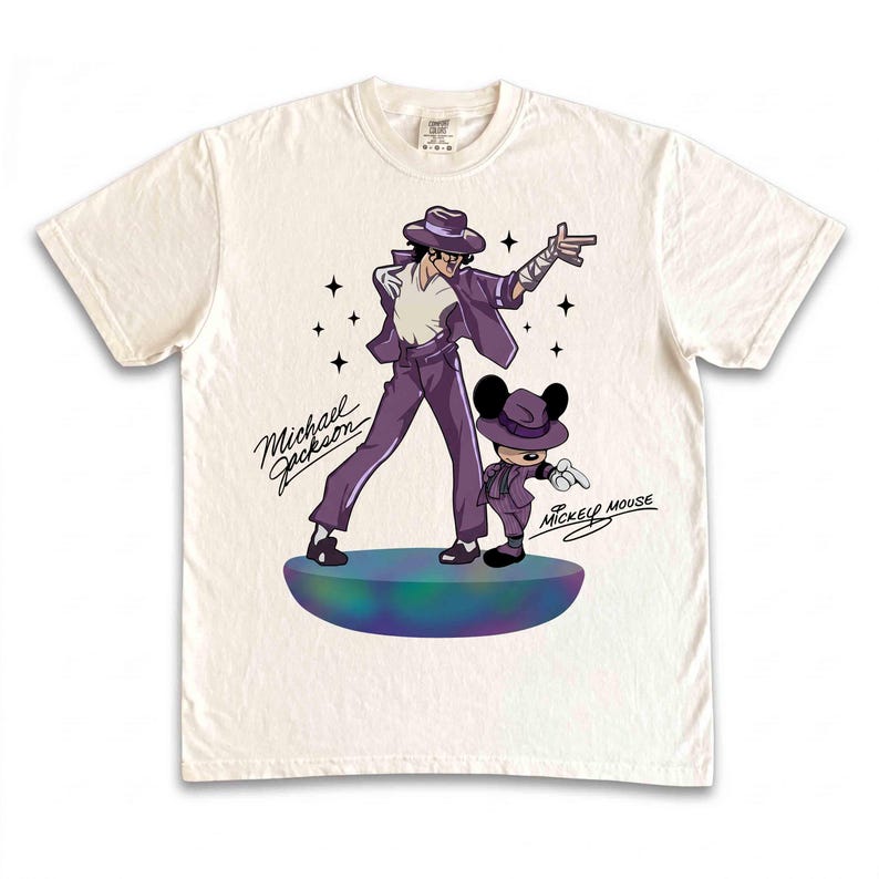May include: Off-white t-shirt featuring a cartoon illustration of Michael Jackson and Mickey Mouse in matching purple outfits. The text "Michael Jackson" and "Mickey Mouse" are written in cursive. The design is on a round, multi-colored platform.
