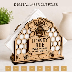Può includere: Un portatovaglioli in legno marrone chiaro con un motivo a nido d'ape tagliato al laser, un'ape centrale e il testo HONEY BEE SWEET AS HONEY BEE HAPPY. Il supporto contiene tovaglioli bianchi ed è mostrato con etichette di formato file.