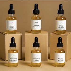 May include: Six clear glass dropper bottles filled with amber-colored fragrance oil. Each bottle features a black dropper cap and a white label with the brand name Sugaplum and scent names: Lavender & Sage, Bamboo & Coconut, White Gardenia, Peppermint & Eucalyptus, Grapefruit & Mint, and Sea Salt & Orchid.