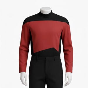 Könnte beinhalten: Ein rotes und schwarzes langärmliges Uniformoberteil und eine schwarze Hose. Das Oberteil hat einen hohen Kragen und ein rotes Feld über Brust und Schultern. Die Hose ist einfarbig schwarz.