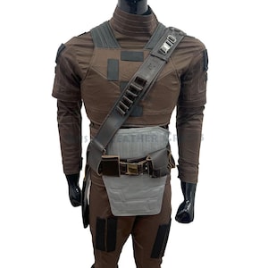 May include: A brown costume with a tactical vest, shoulder strap, and belt. The outfit includes a brown long-sleeved shirt and trousers. The costume has a grey and brown colour scheme, with black accents.