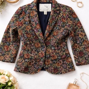 May include: A floral-patterned blazer with a navy blue lining and a single-button closure. The jacket features a tapestry-like design with roses in shades of red, orange, and purple. The label reads "Table Rock".