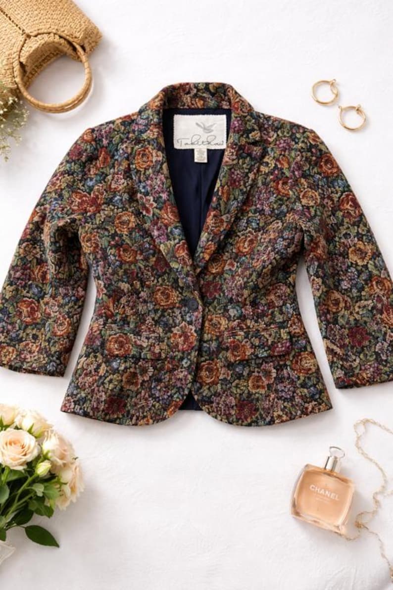 May include: A floral-patterned blazer with a navy blue lining and a single-button closure. The jacket features a tapestry-like design with roses in shades of red, orange, and purple. The label reads "Table Rock".