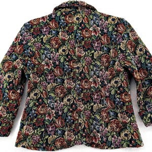 May include: A floral tapestry blazer featuring a vibrant pattern of red, pink, blue, and green flowers on a black background. The jacket has a classic collar and three-quarter sleeves, offering a vintage aesthetic.