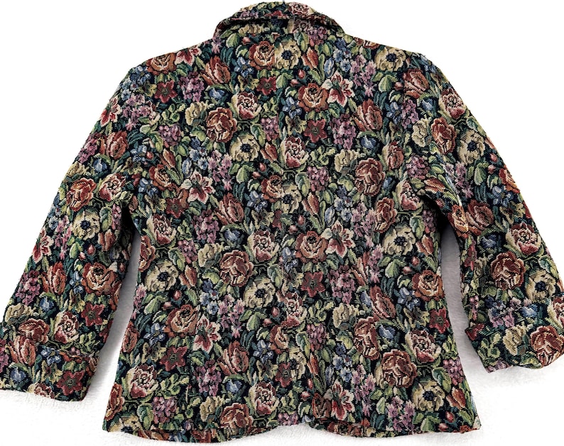 May include: A floral tapestry blazer featuring a vibrant pattern of red, pink, blue, and green flowers on a black background. The jacket has a classic collar and three-quarter sleeves, offering a vintage aesthetic.