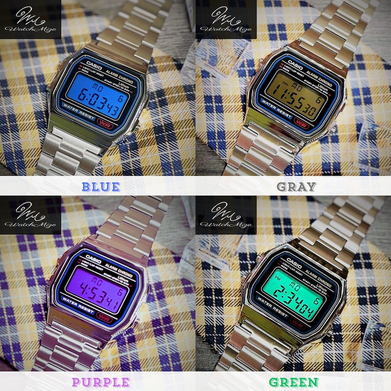 May include: Four digital Casio watches with silver straps and various coloured digital displays: blue, grey, purple, and green. Each watch has the Casio logo and text on the face. The watches are displayed on a plaid background.