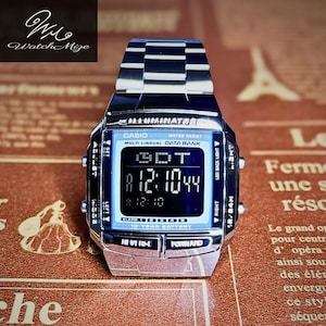 May include: A silver Casio digital watch with a rectangular face and a stainless steel band. The watch displays the time and date on a digital screen. The watch has the text "CASIO" and "WATER RESIST" on the face.