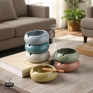 May include: A collection of ceramic ashtrays in various colors, including blue, green, and yellow. One ashtray holds a lit cigarette. The ashtrays are stacked and arranged on a wooden surface, with smoke rising from one.