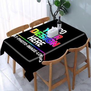 May include: A rectangular black tablecloth featuring a vibrant rainbow-colored gradient text that reads YOUR DESIGN HERE and XT-PHOTO-IMAGE-LOGO. A white tissue box and a wine bottle are placed on the surface of the table, which is surrounded by chairs.