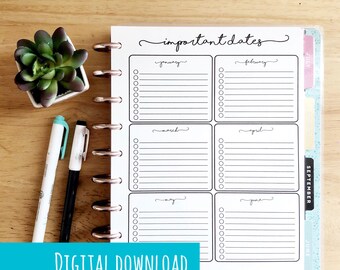 May include: A white planner page with the words "important dates" in cursive. The page is divided into boxes for each month, with lines for notes and check boxes. A small succulent and two pens are on the wooden surface.