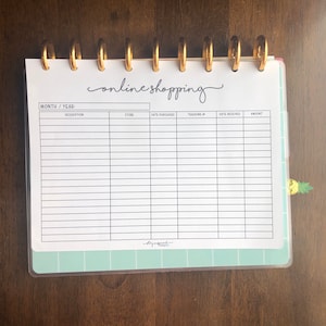 May include: A white sheet of paper with a grid pattern and the words "online shopping" written in cursive. The sheet is labeled with the headings "Month/Year", "Description", "Store", "Date Purchased", "Tracking #", "Date Received", and "Amount".