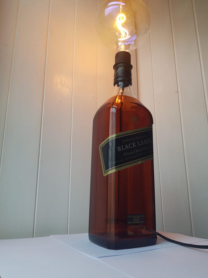 May include: A repurposed lamp made from a Johnnie Walker Black Label whiskey bottle. The brown glass bottle has a black label and a large, round lightbulb. The lamp is plugged in and ready to use.