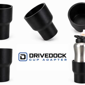 May include: Black cup adapter with the text "DRIVEDOCK CUP ADAPTER". The adapter is designed to hold a variety of cup sizes. The image shows the adapter from multiple angles, including one with a water bottle.