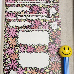 May include: A set of six blank cards with a floral border. The border features pink, red, orange, yellow, and purple flowers on a black background. The text "Stamp for Reply" is printed on each card.