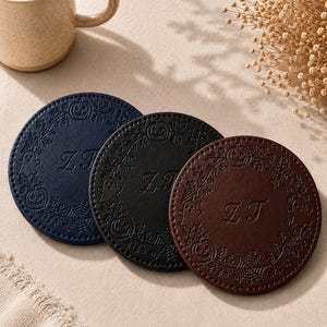 May include: Three circular coasters in navy blue, black, and brown, each featuring an embossed wreath design with pumpkins, ghosts, and spiderwebs. The center of each coaster displays the monogrammed letters ZT in a decorative script font.
