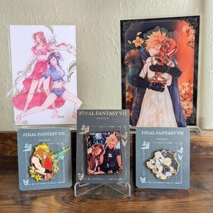 May include: A collection of Final Fantasy VII merchandise including two acrylic character stands and three enamel pins on backing cards. The items feature illustrations of Cloud Strife and Aerith Gainsborough in various poses and artistic styles.
