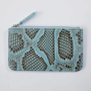 May include: A rectangular, light blue and brown snakeskin-patterned wallet with a zipper closure. The wallet has a light blue zipper pull and a silver-colored zipper. The snakeskin pattern is a mix of light blue and brown.