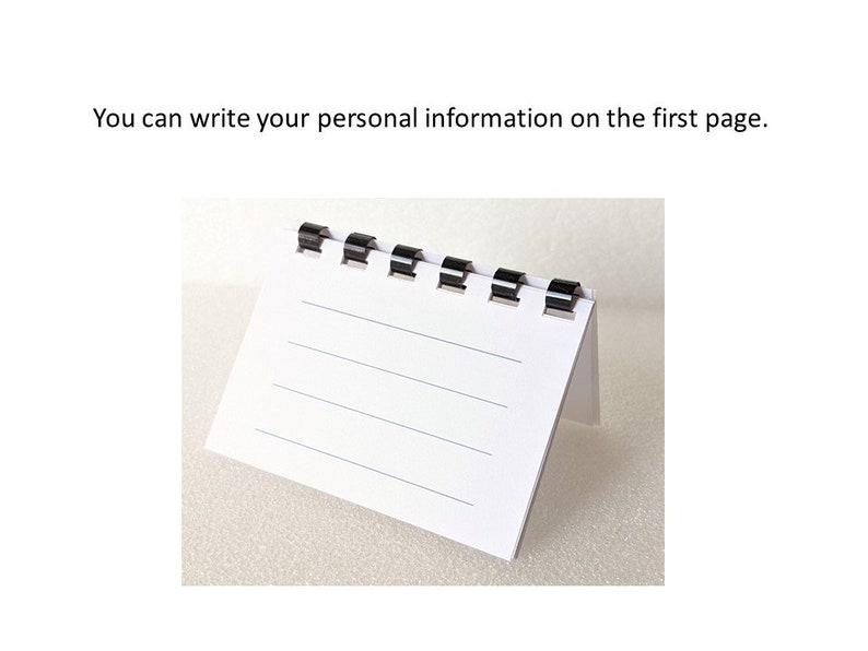 May include: A small, white, lined notepad with black binding. The notepad is standing upright, with the first page visible. The text "You can write your personal information on the first page" is above the notepad.