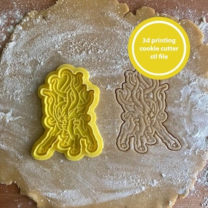 May include: A yellow 3D-printed cookie cutter in the shape of a stylized creature, next to a cookie cut-out. The text "3D printing cookie cutter stl file" is in a yellow circle. The cutter is on a surface dusted with flour.