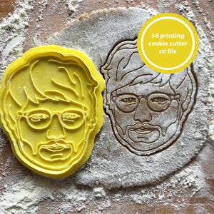 May include: A yellow plastic cookie cutter in the shape of a man's face with glasses and a mustache. Next to it is a cookie cut out of dough in the same shape. The image includes the text: "3d printing cookie cutter stl file."