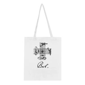 Könnte beinhalten: Weiße Tragetasche mit einem schwarzen Notenmuster in Kreuzform und dem Namen "Bach" darunter. Die Tasche hat lange weiße Henkel. Ein stilvolles Accessoire für Musikliebhaber.