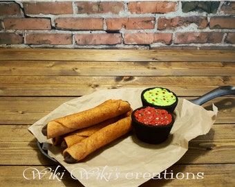 May include: Four brown and orange rolled tacos on a brown paper-lined black cast iron skillet with a small bowl of red salsa and a small bowl of green guacamole with red and green sprinkles. The skillet is on a wooden surface.