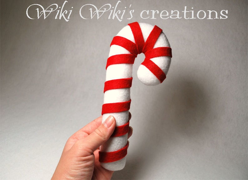 May include: A white and red felt candy cane ornament. The candy cane is about 12 inches long and has a red and white striped pattern.