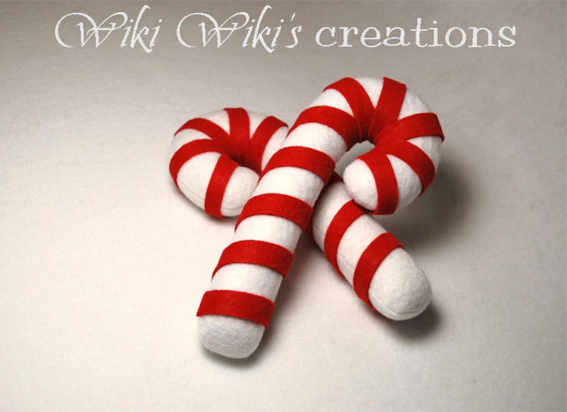 May include: Two red and white striped felt candy canes. The candy canes are crossed over each other.